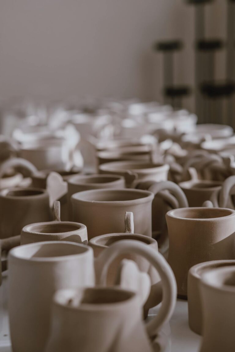 A focused view of handcrafted clay mugs in a pottery workshop.