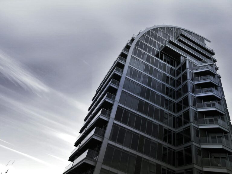 A striking modern building with a glass facade showcases innovative architectural design.