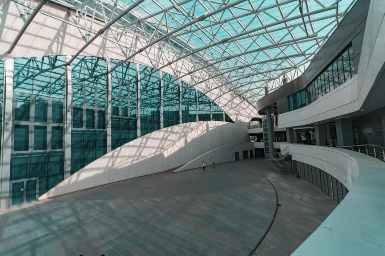 Spacious indoor atrium with modern glass and steel architecture, showcasing a futuristic design.